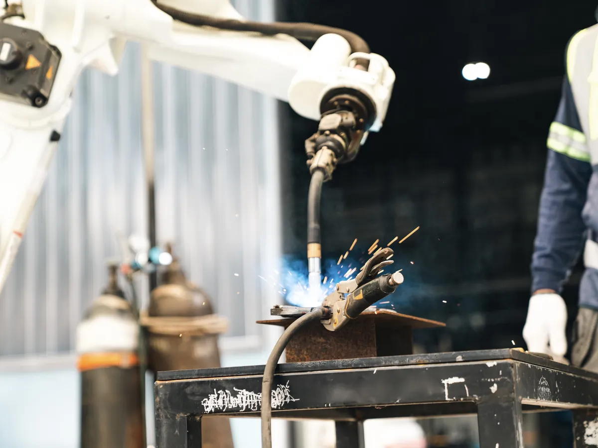 Industrial robot welding metal with bright sparks in a workshop setting