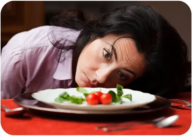 woman looking at plate with little food on it