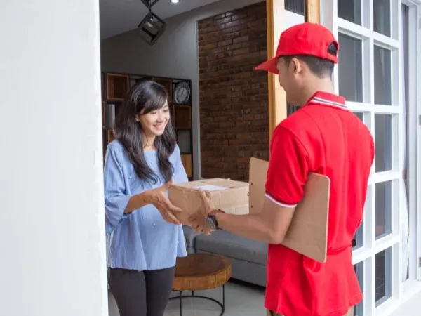 Smiling woman receiving weight loss medication package delivered to her home.