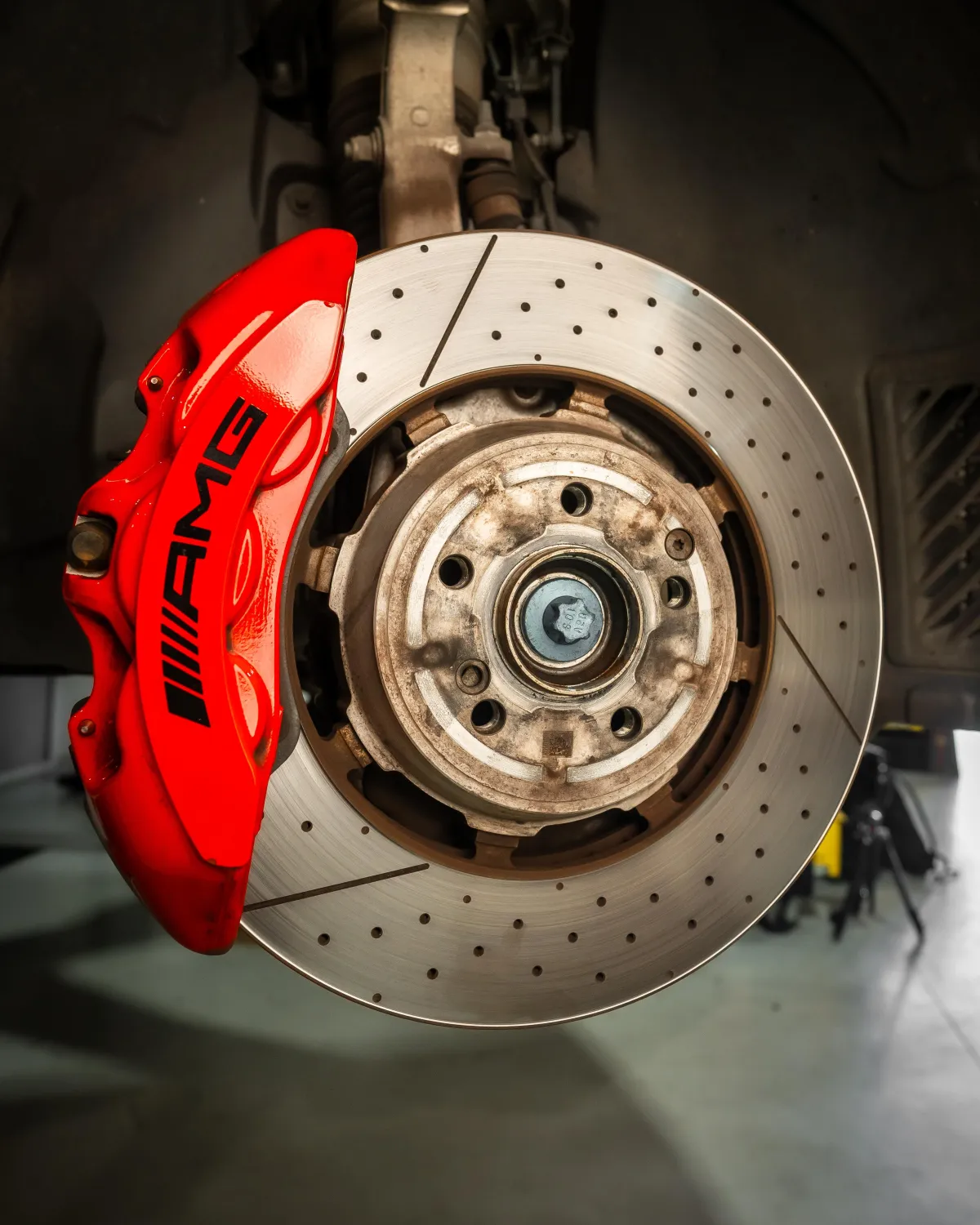 Technician replacing front brake rotors and pads on Mercedes Benz in Cranbourne workshop.