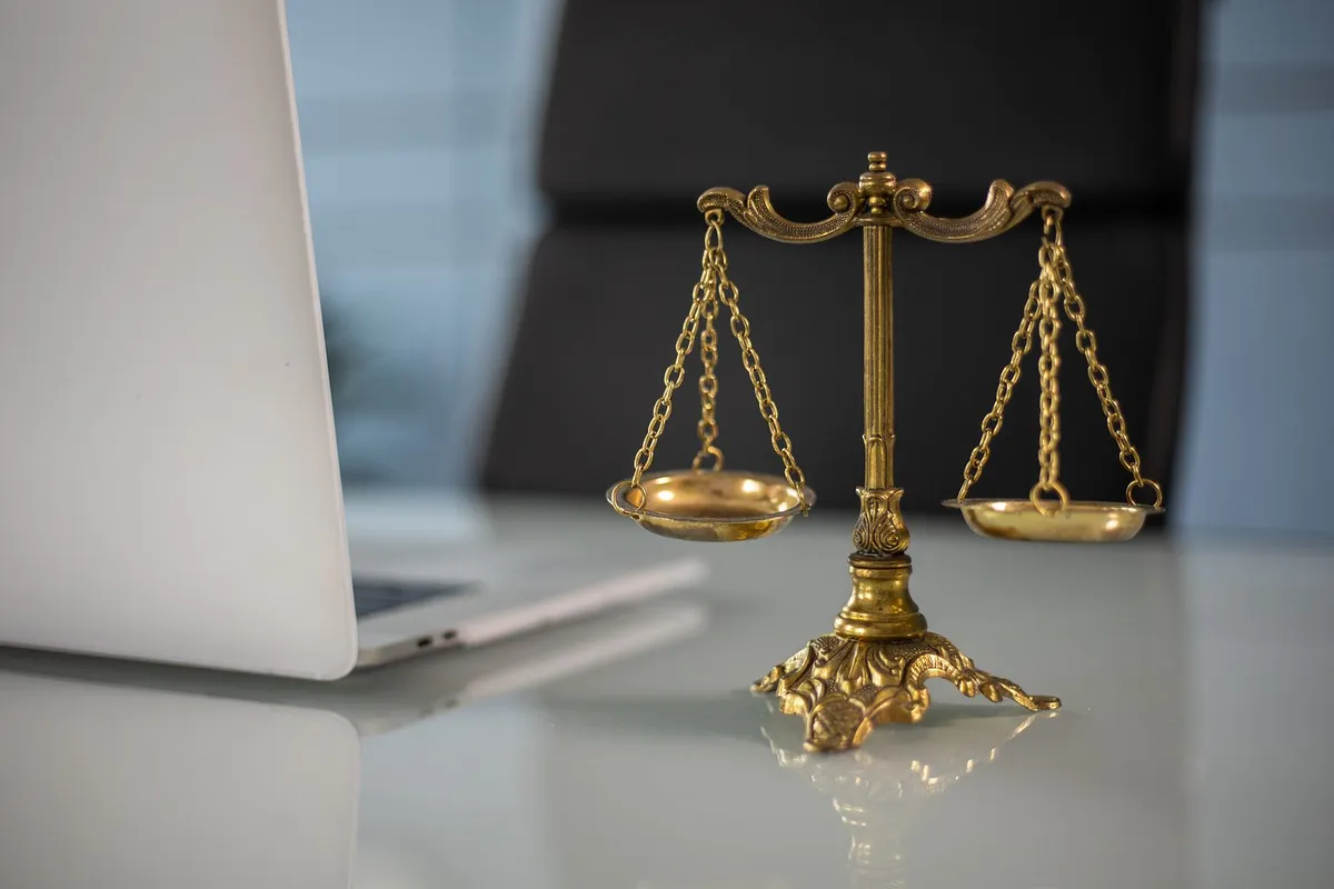 A balance scale on a desk beside a laptop