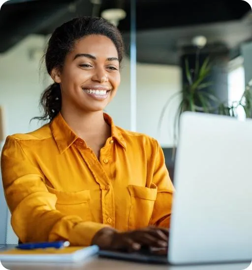 Happy businesswoman using laptop typing and working online while sitting at workplace in office