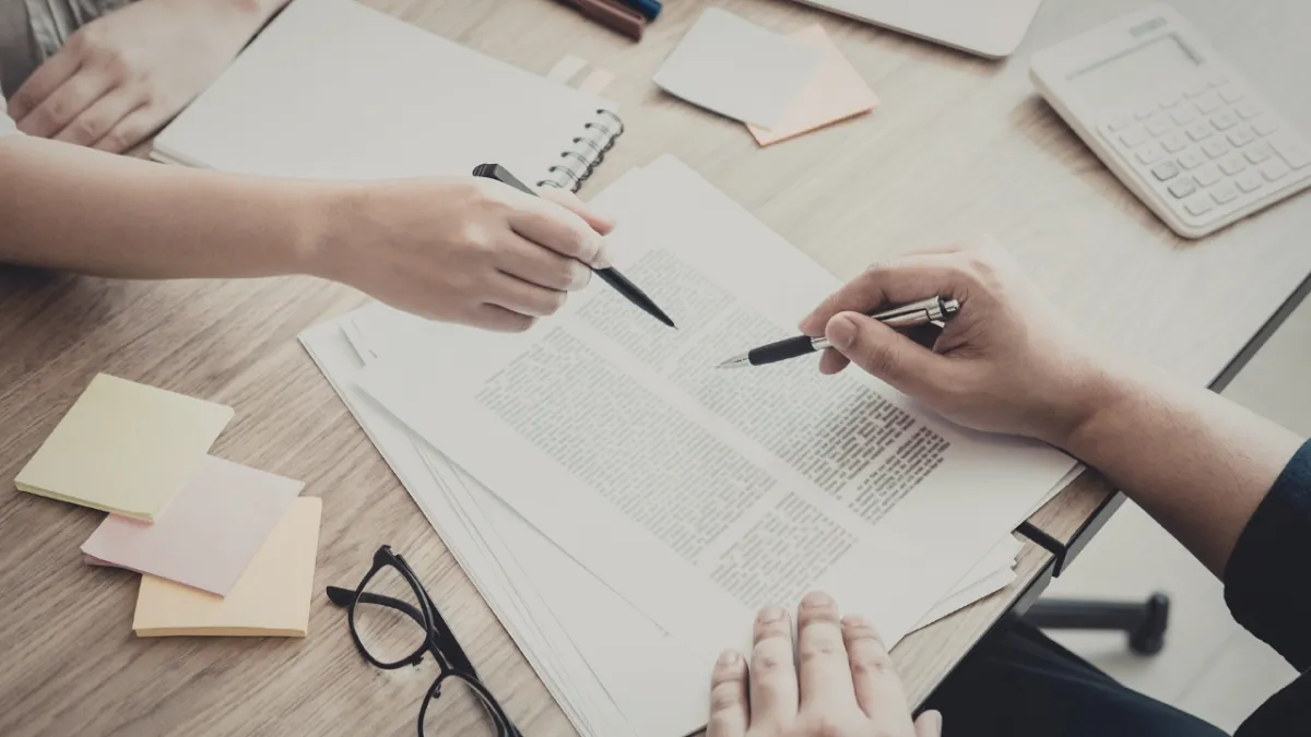 Buyer signing documents at closing table in Pensacola Florida with real estate agent