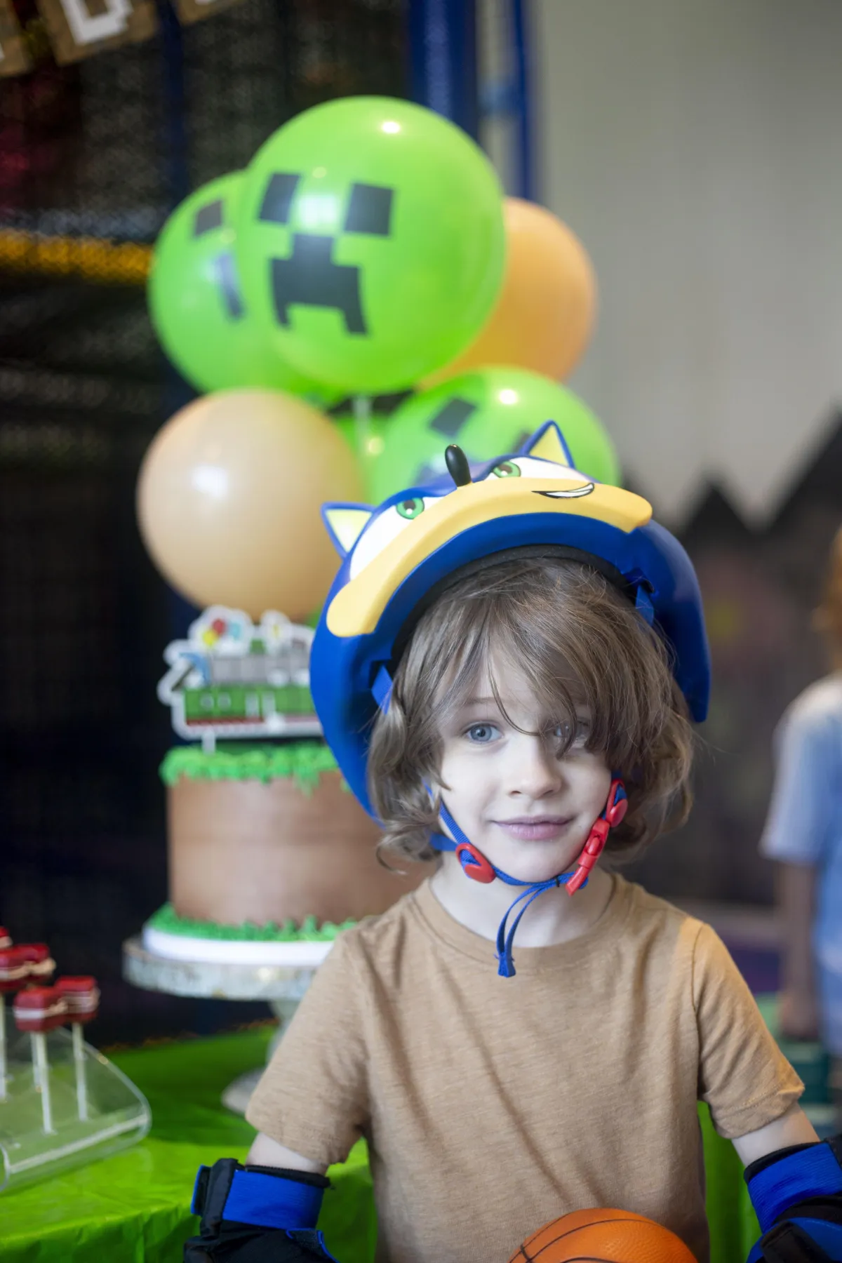 Young boy standing next to a Minecraft-themed birthday cake at Wild Child indoor playground in Bastrop, TX