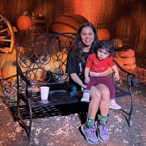 Monica Contreras, play coach at Wild Child Bastrop, sitting on a bench with her one-year-old child