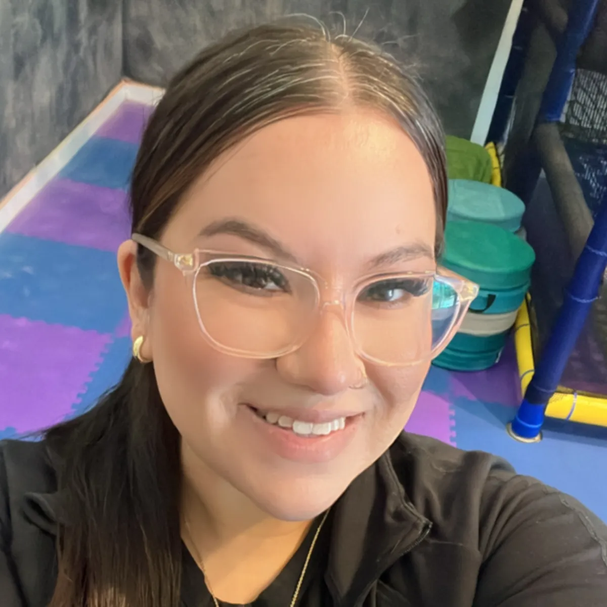 Daisy Garza, play coach at Wild Child Bastrop, standing in front of the indoor playscape with a welcoming smile