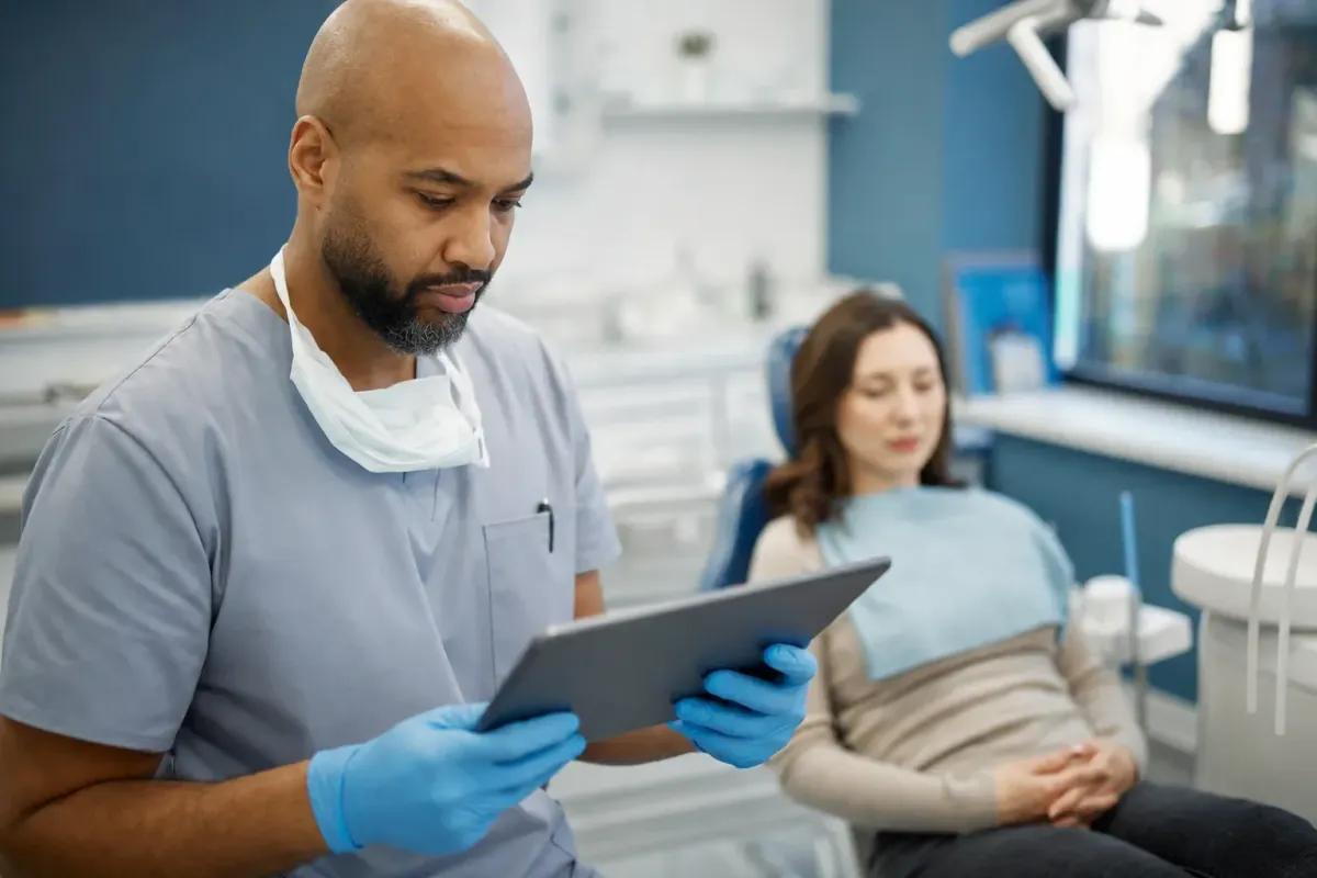 Dental provider reviewing a patient's medical history on a tablet before sedation
