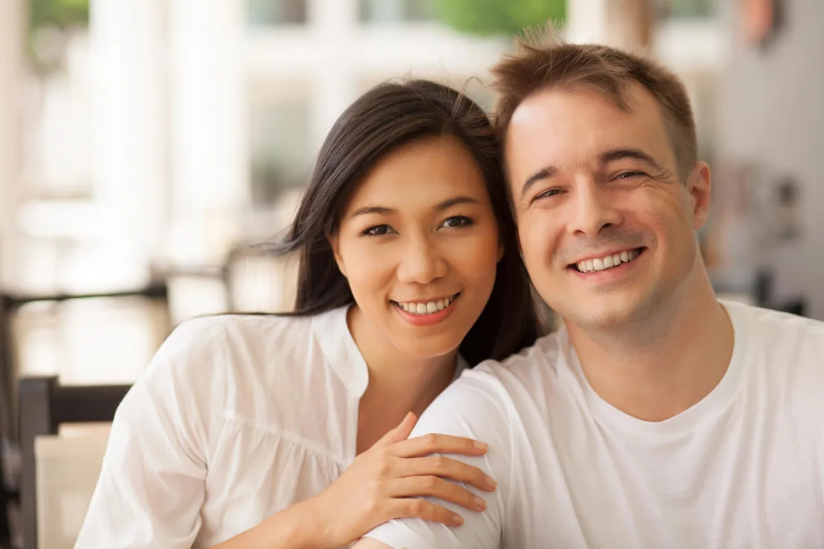 Smiling couple sitting closely together in a bright café, showing emotional connection and relationship harmony