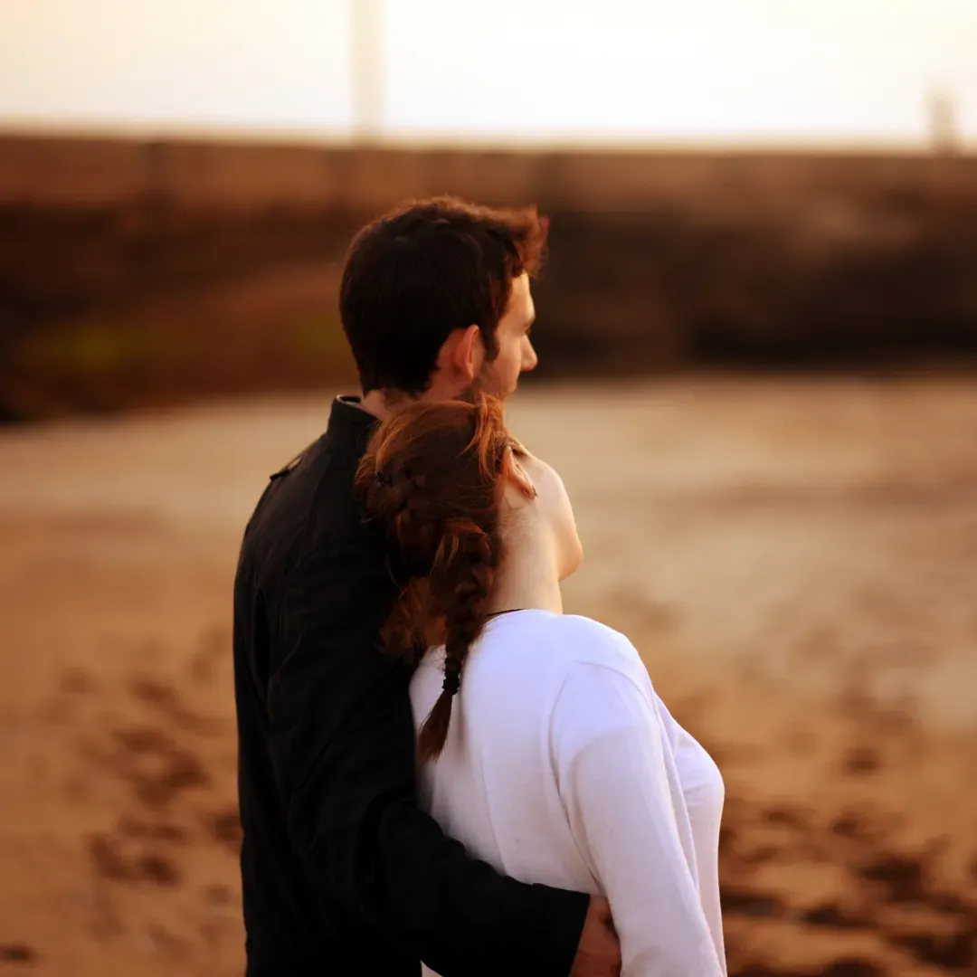 Couple embracing on the beach at sunset, symbolizing reconnection, healing, and emotional safety in relationships