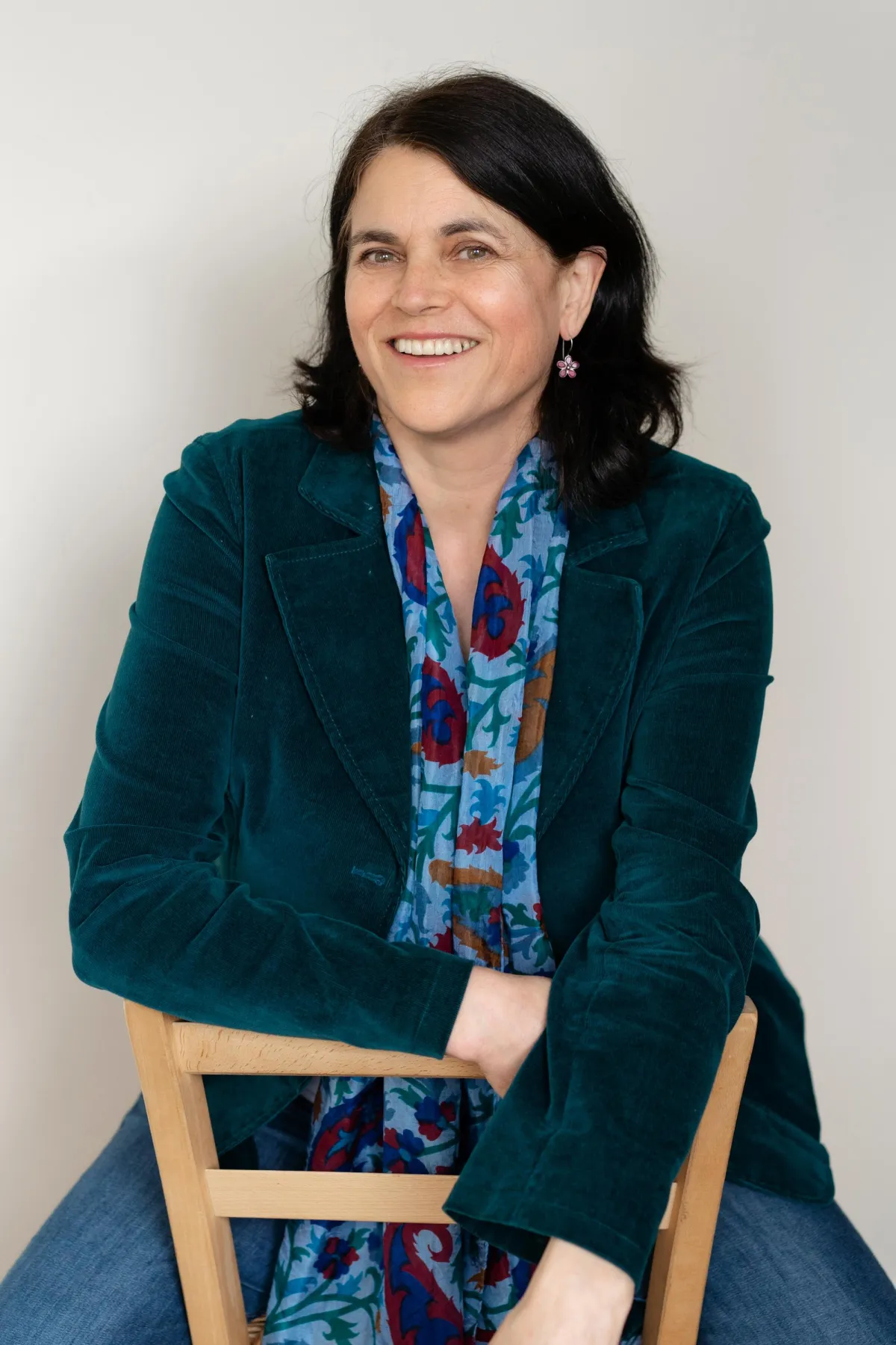 Smiling woman seated comfortably on a chair, exuding warmth and confidence.