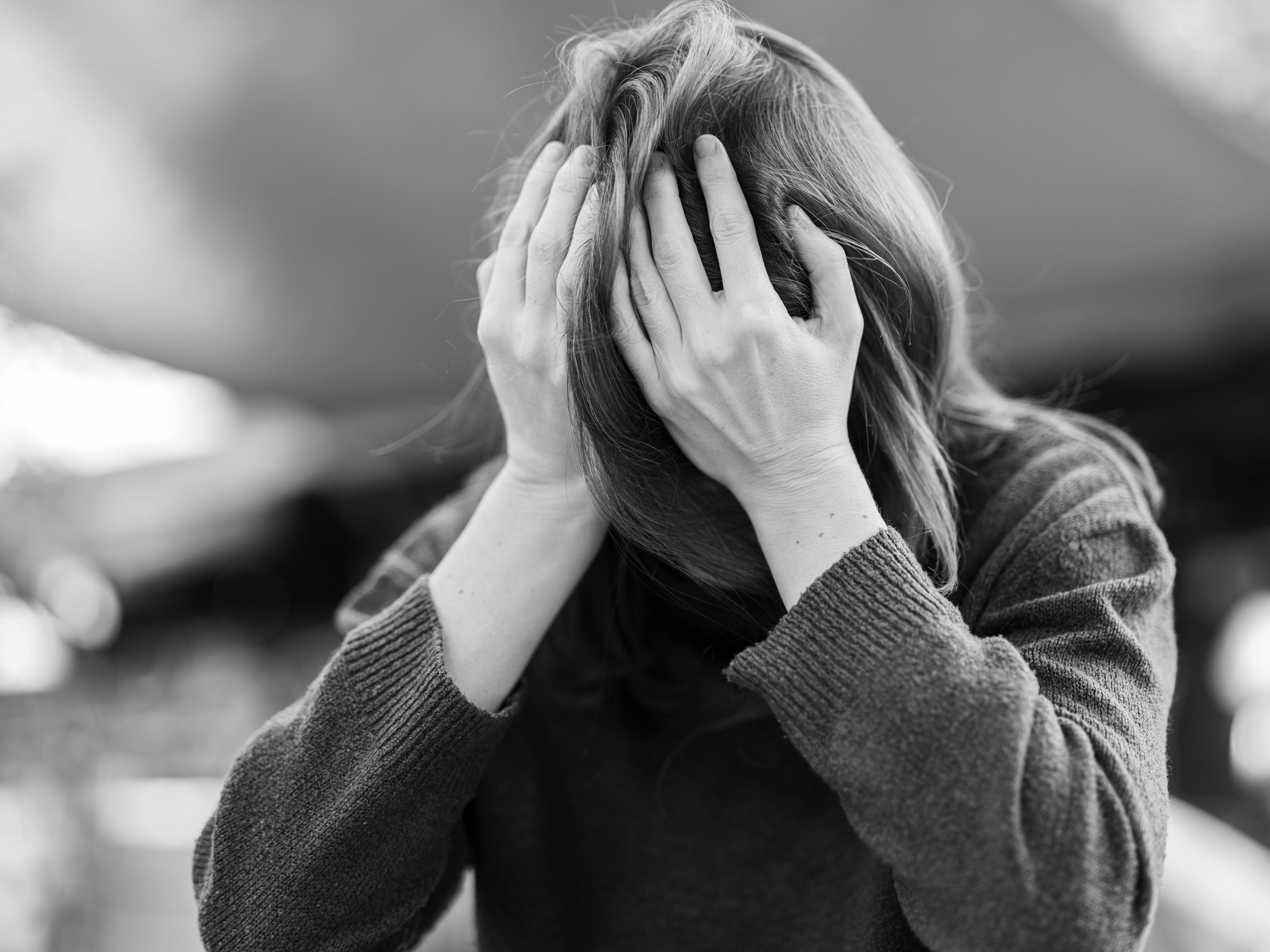 Black and white portrait of a distressed woman holding her head, representing emotional overwhelm, relationship struggles, anxiety, and mental health challenges.