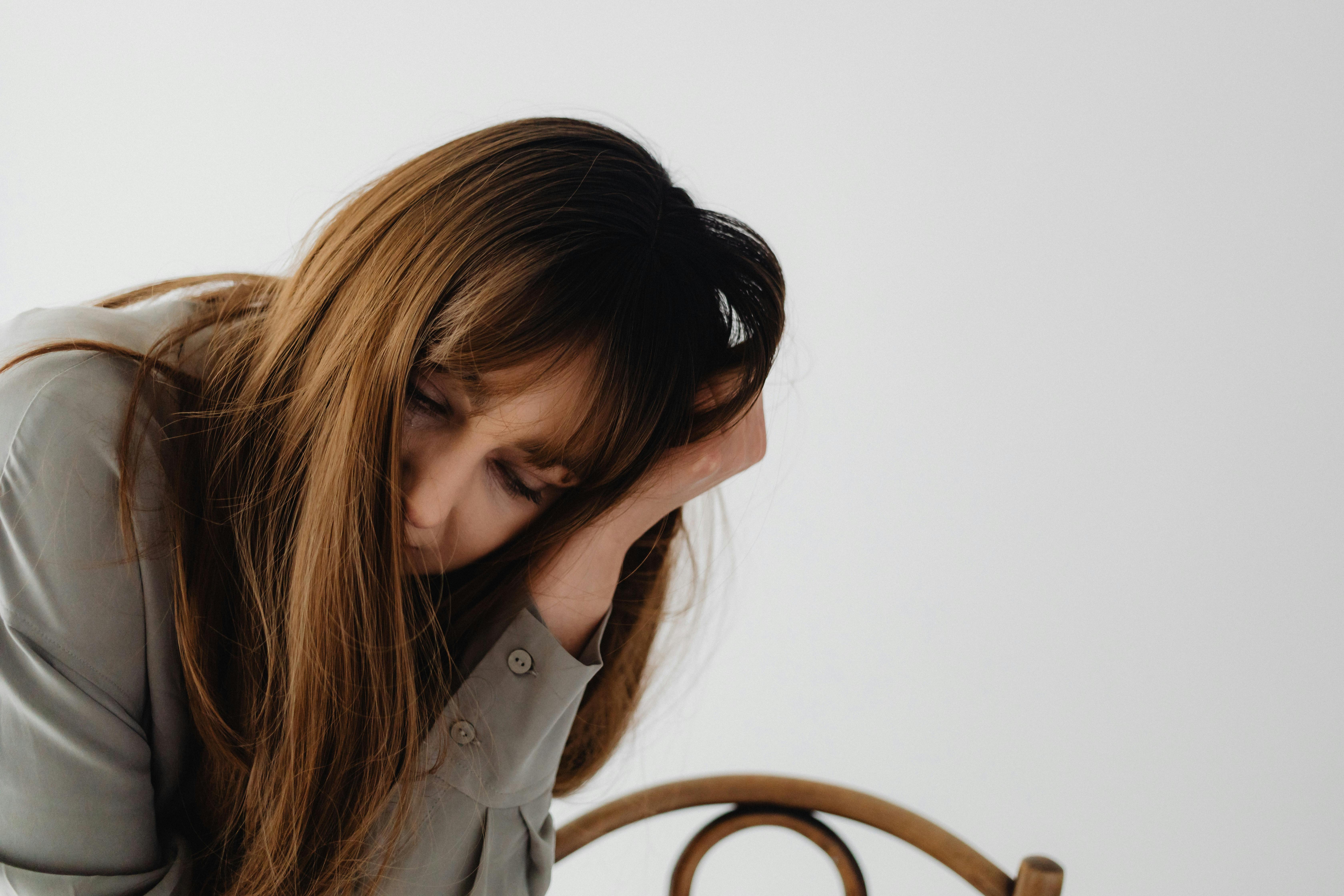 Thoughtful woman resting her head on her hand while sitting on a chair, illustrating emotional fatigue, heartbreak recovery, reflection, and personal transformation.