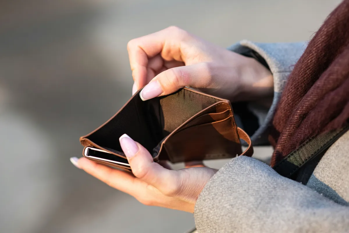 Person holding open an empty wallet with no cash inside.