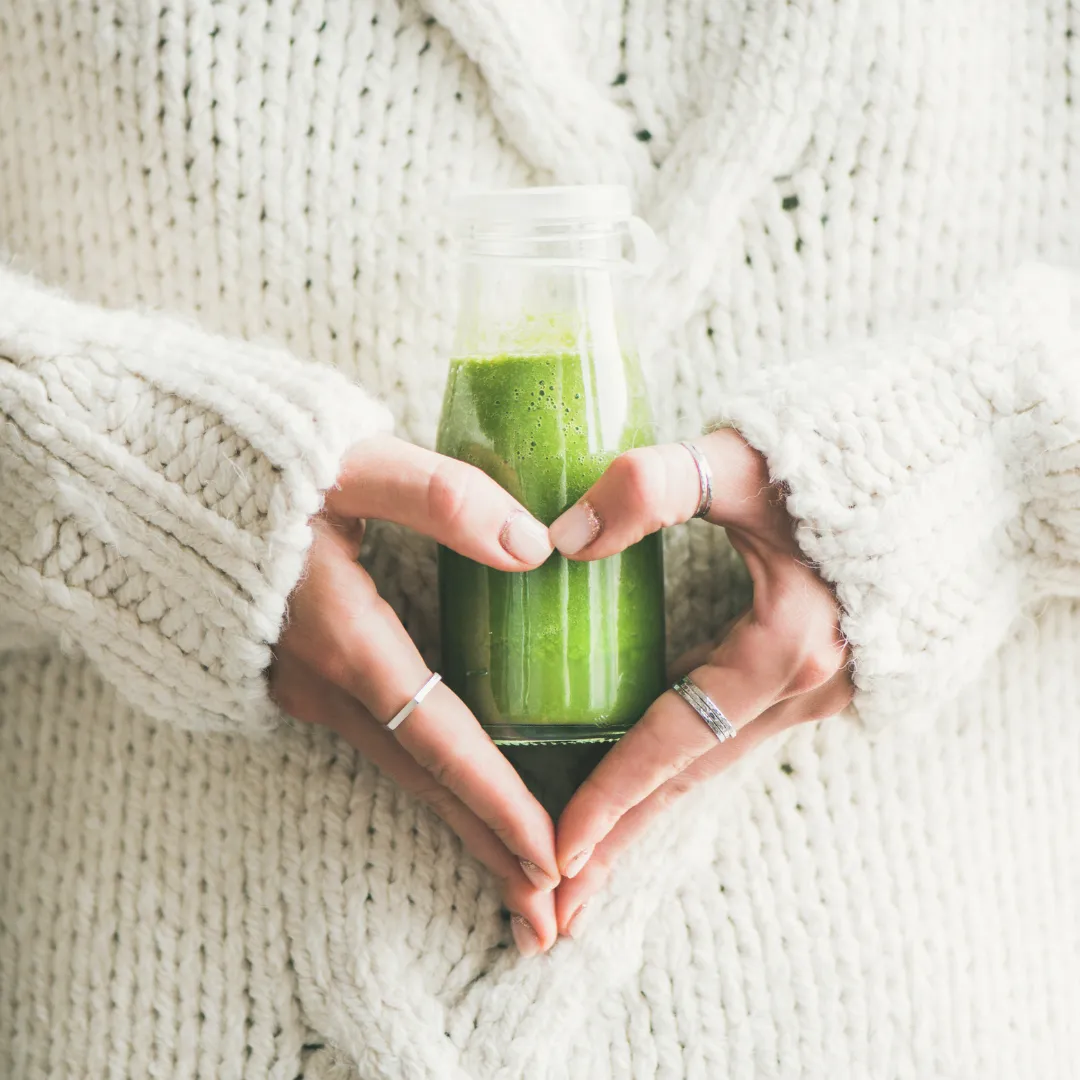 Hands forming a heart around a green smoothie bottle, representing detox and gentle healing through homeopathy in Brighton