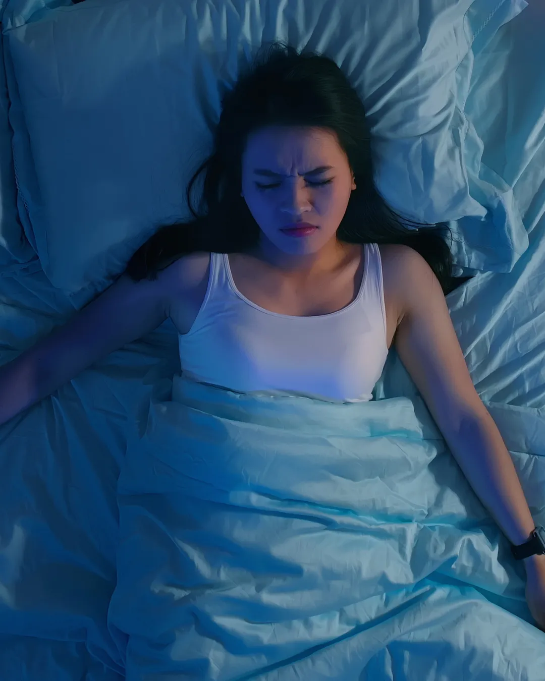 Woman lying in bed at night, unable to sleep or having a nightmare