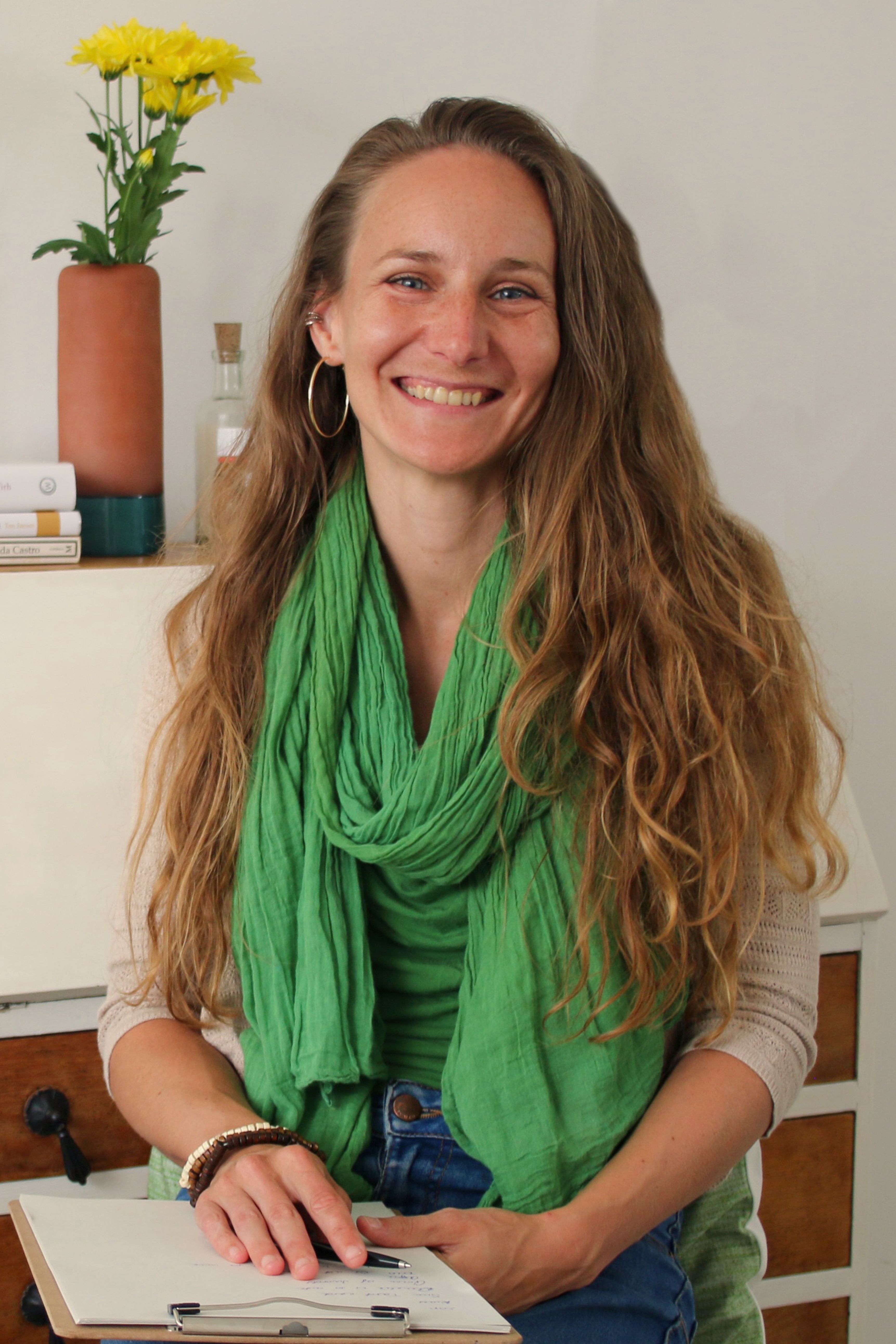 Anna Bihari, Brighton-based homeopath, smiling warmly in her clinic wearing a green scarf