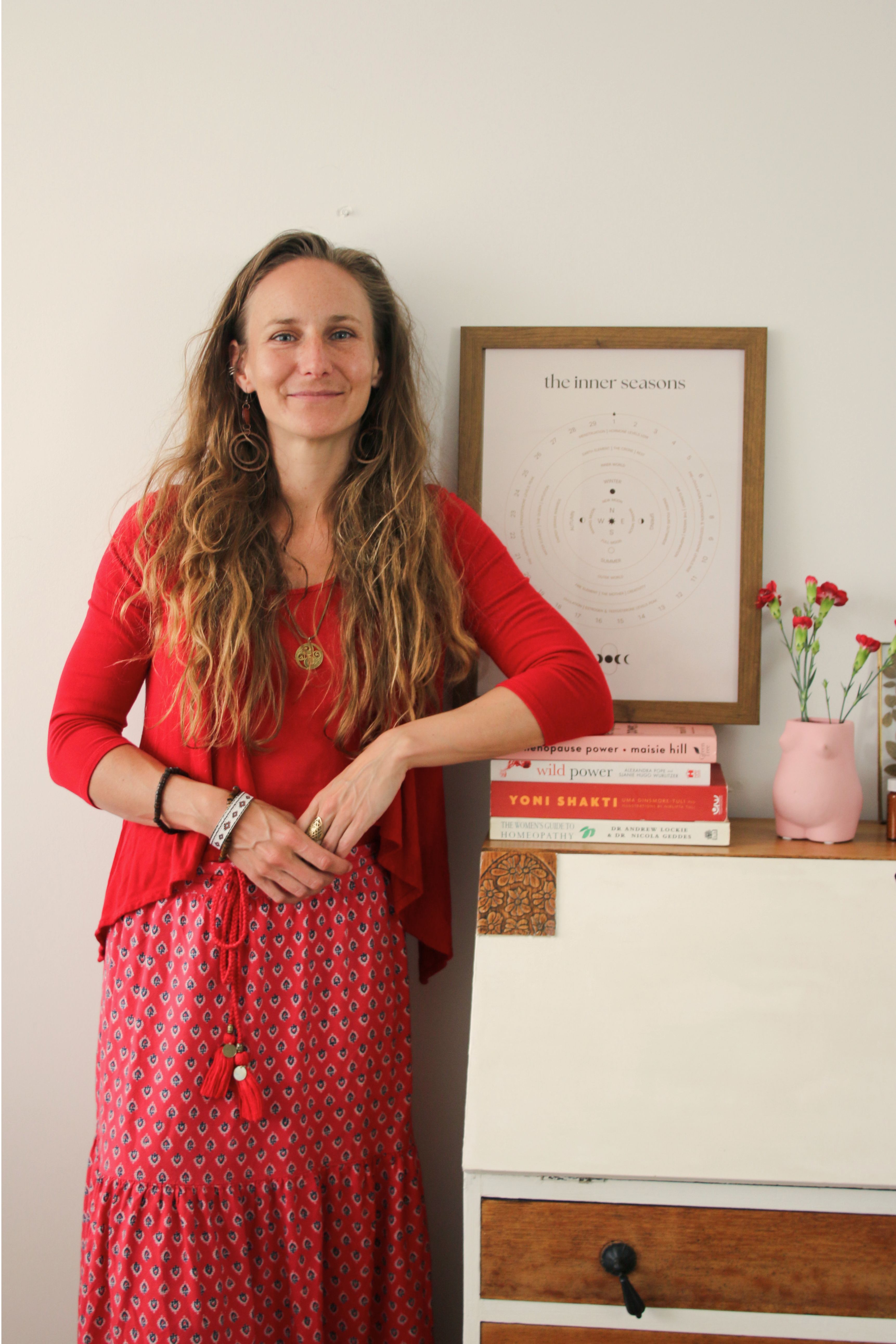 Brighton homeopath Anna Bihari standing in clinic beside menstrual cycle chart