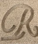 Close-up of the Buff cast stone finish, a sandy color with a letter 'R' carved to show texture.