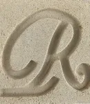 Close-up of the Limestone cast stone finish, a color with a letter 'R' carved to show texture.