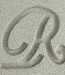 Close-up of the Gray cast stone finish, a color with a letter 'R' carved to show texture.