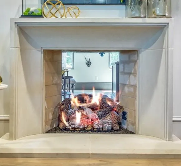 The Patricia see-through fireplace, featuring an elegant stone surround and acting as a stunning divider between two rooms.