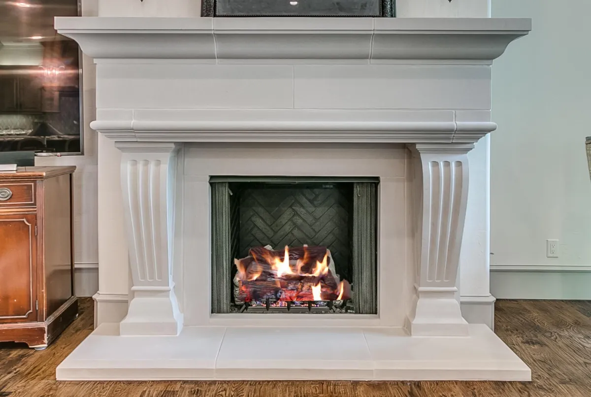 The Flauto Toro, a neoclassical stone fireplace defined by its strong, fluted columns and a grand, molded mantel.