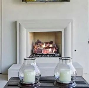 The Hector Design, a modern white fireplace with a sleek mantel and a view of the fire.