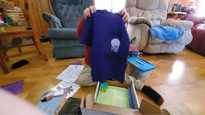 Excited student holding up their t-shirt from heir welcome kit