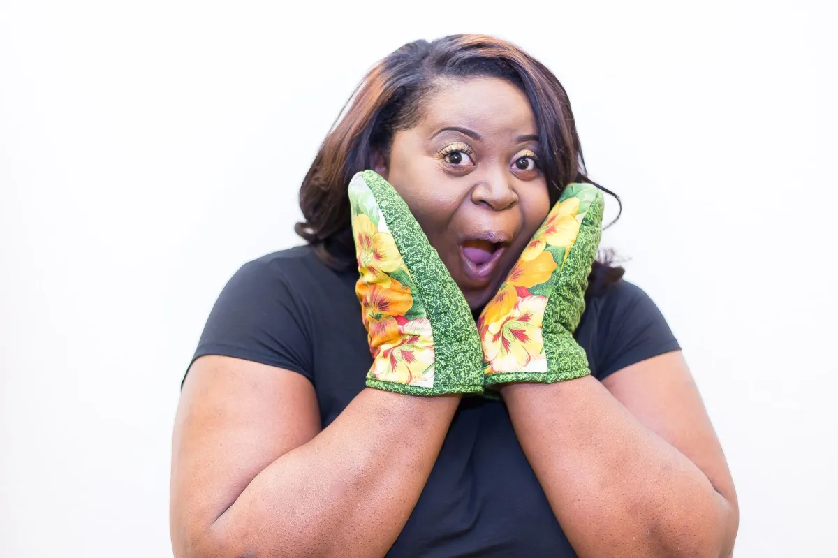 Teacher wearing oven mitts demonstrating a fun and interactive family cooking class