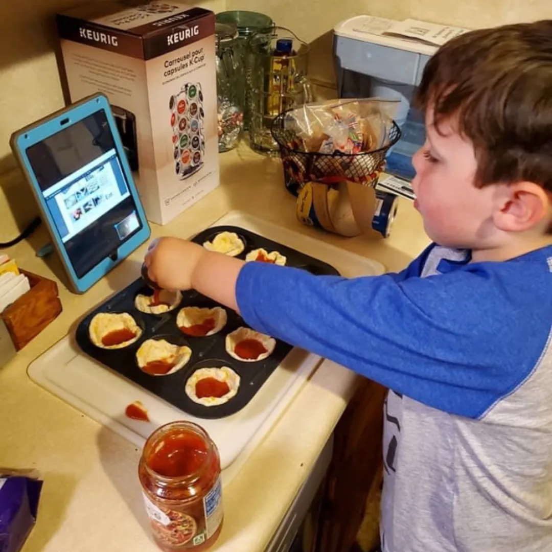 Teacher wearing oven mitts demonstrating a fun and interactive family cooking class