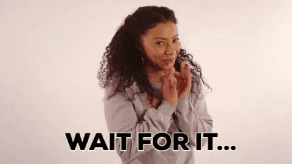 Woman clasping her hands with an excited, expectant expression as the words “WAIT FOR IT…” appear across the bottom.