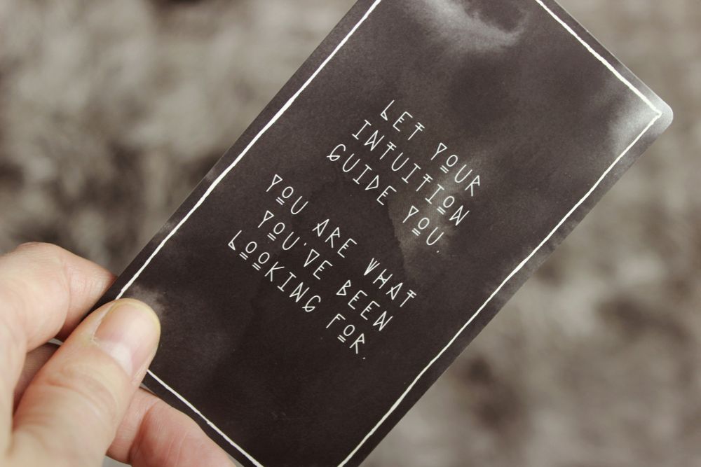 Hand holding a black card that reads, “Let your intuition guide you. You are what you’ve been looking for.”