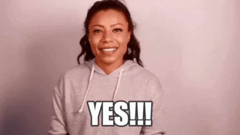 Smiling woman in a gray hoodie faces the camera as the bold word “YES!!!” appears across the bottom.