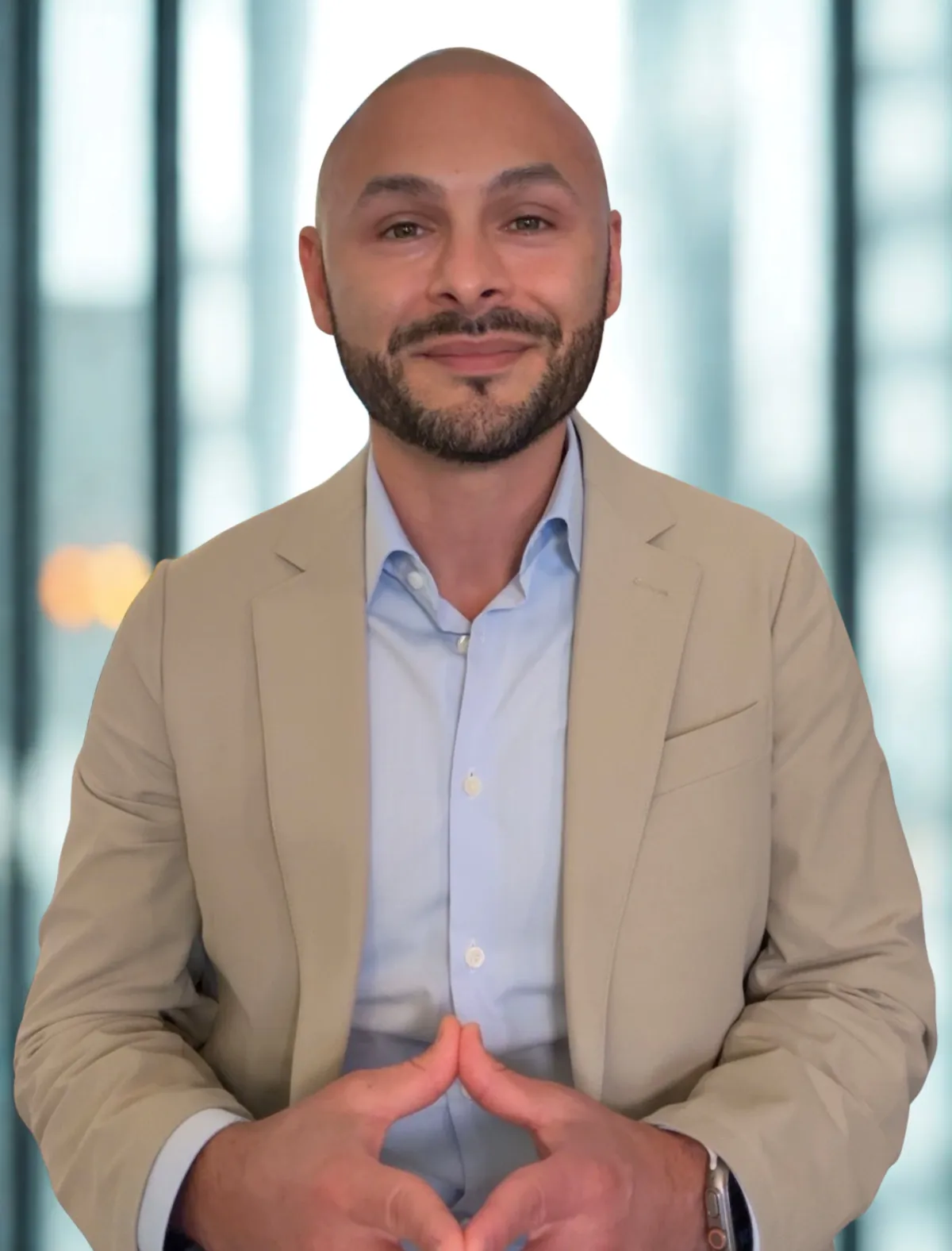 Javier Chávez, professional recruiter, smiling in a modern workspace with a laptop and notepad, exuding confidence and approachability. Javier is Latino, mid-30s, wearing a blue blazer. The background is softly blurred, emphasizing his focus and professionalism.