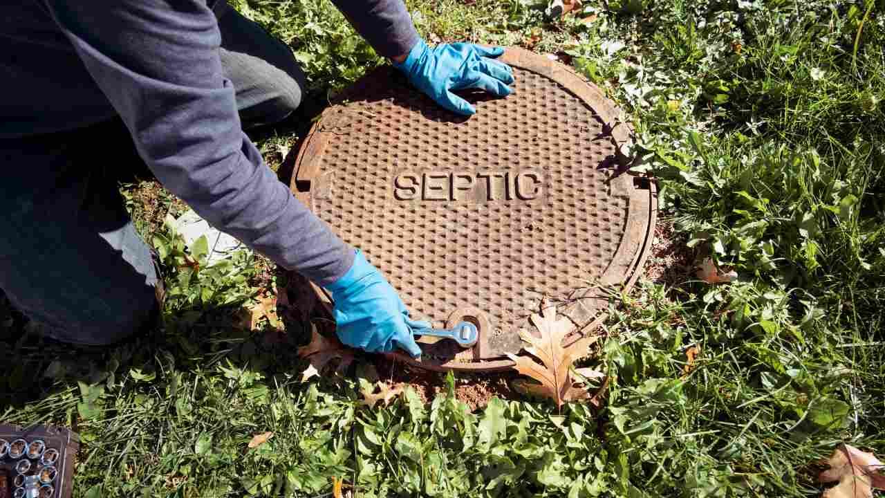 Septic tank servicer opening a manhole cover.