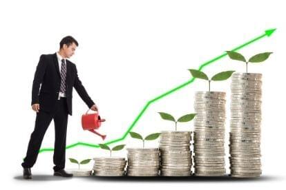 man watering plants growing stacks of coins