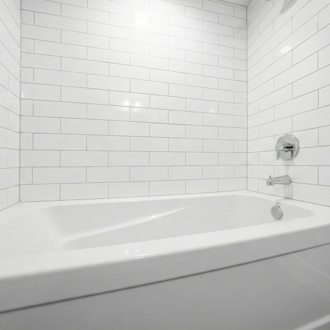 A minimalist bathroom corner featuring a high-gloss white acrylic bathtub set against clean white subway tiles. / A minimalist bathroom corner featuring a high-gloss white acrylic bathtub set against clean white subway tiles.