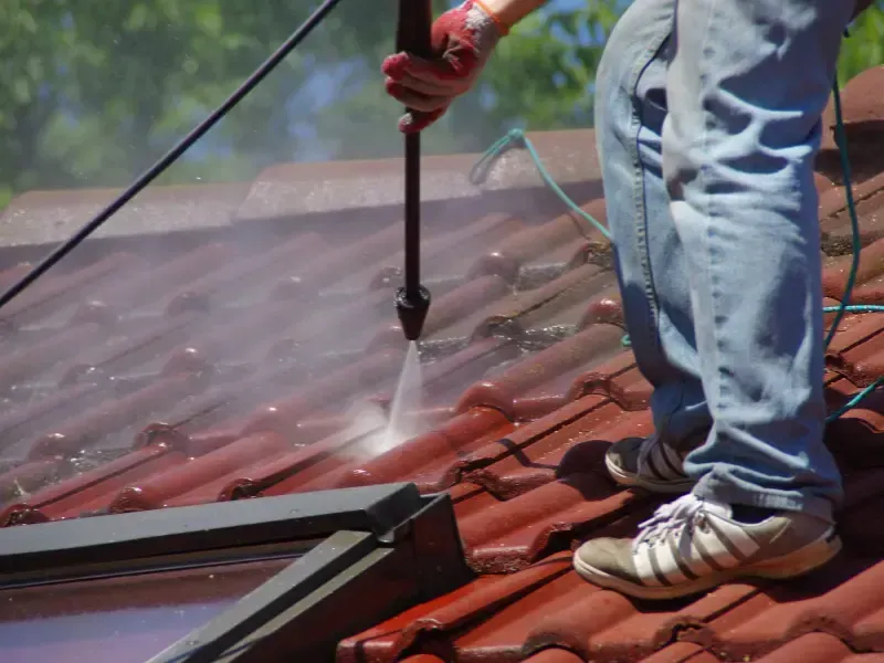 High-pressure washer wand directed at a tile roof, a method that strips granules from asphalt shingles