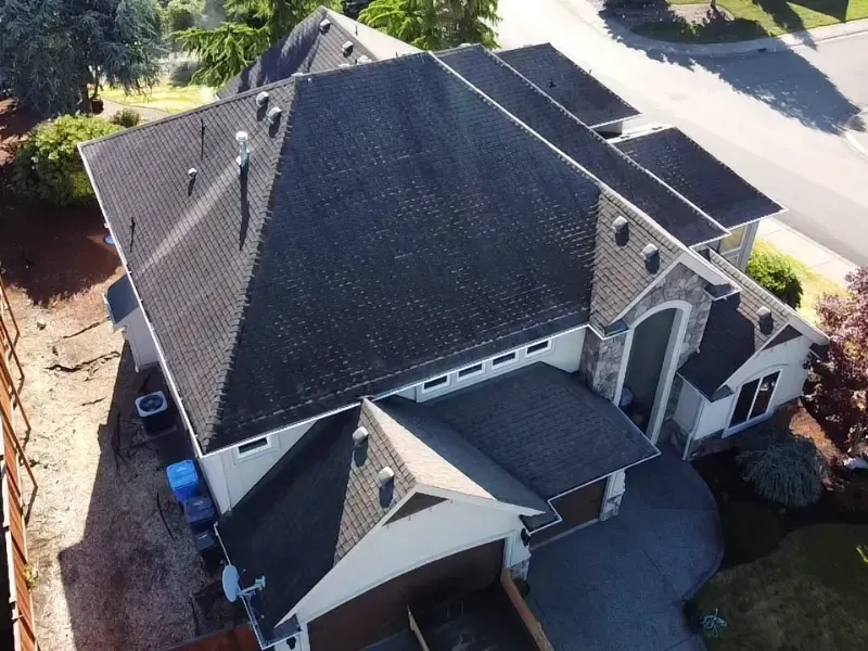 Aerial view of a dark shingle roof with vents and valleys on a large residential home.