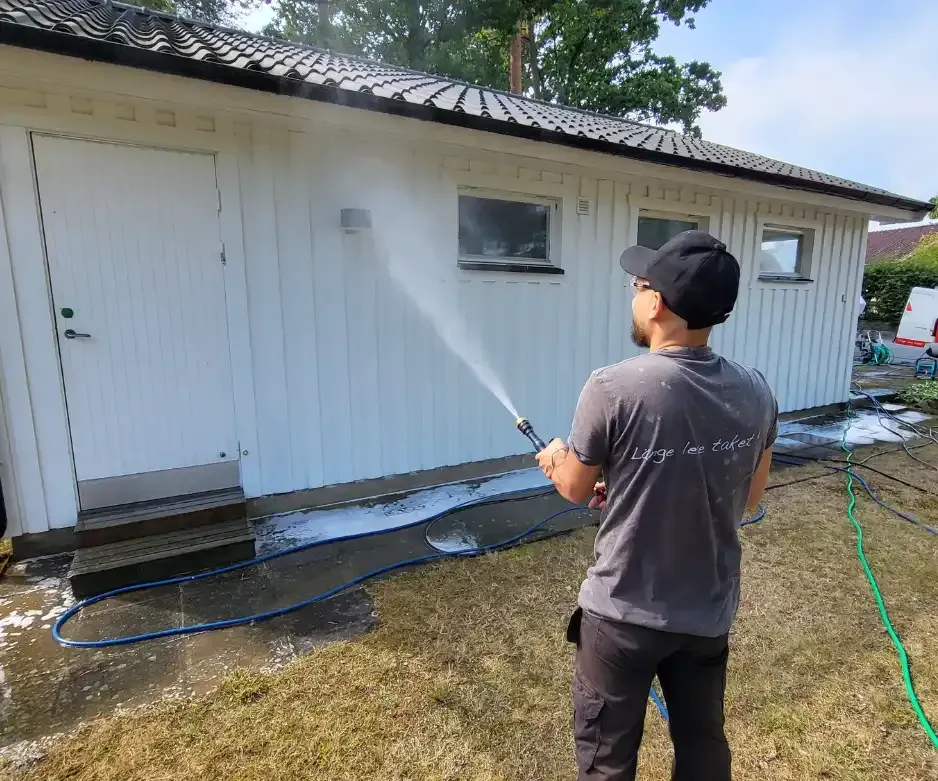 Fasadtvätt med softwash-metod på putsad träfasad.