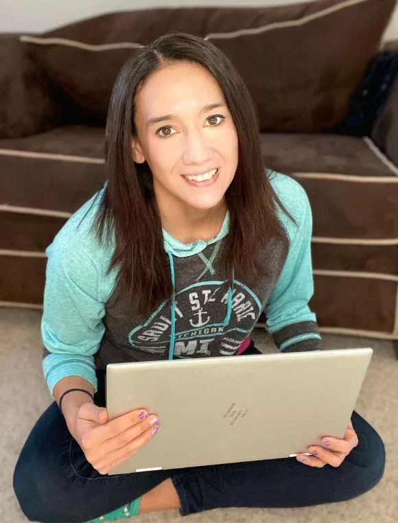 dark haired woman sitting on floor with laptop