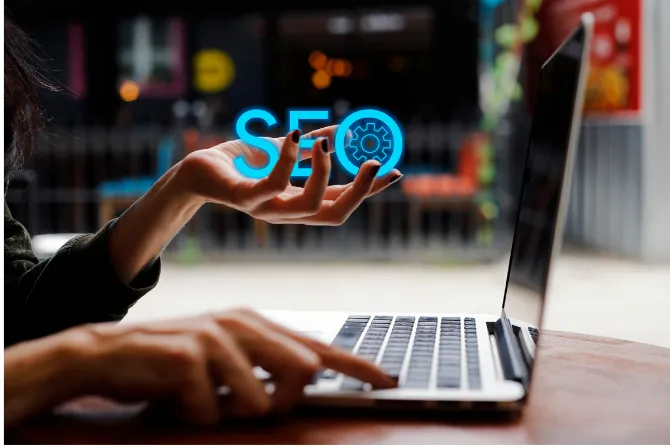 Hand using a laptop with an SEO optimization icon on the screen