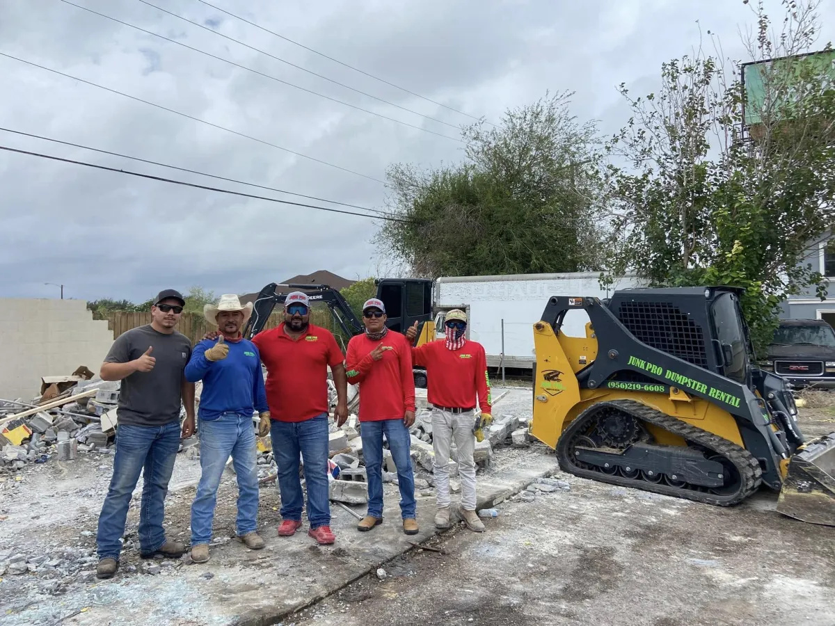 JunkPro CEO Victor standing with the team in front of heavy demolition equipment in the Rio Grande Valley