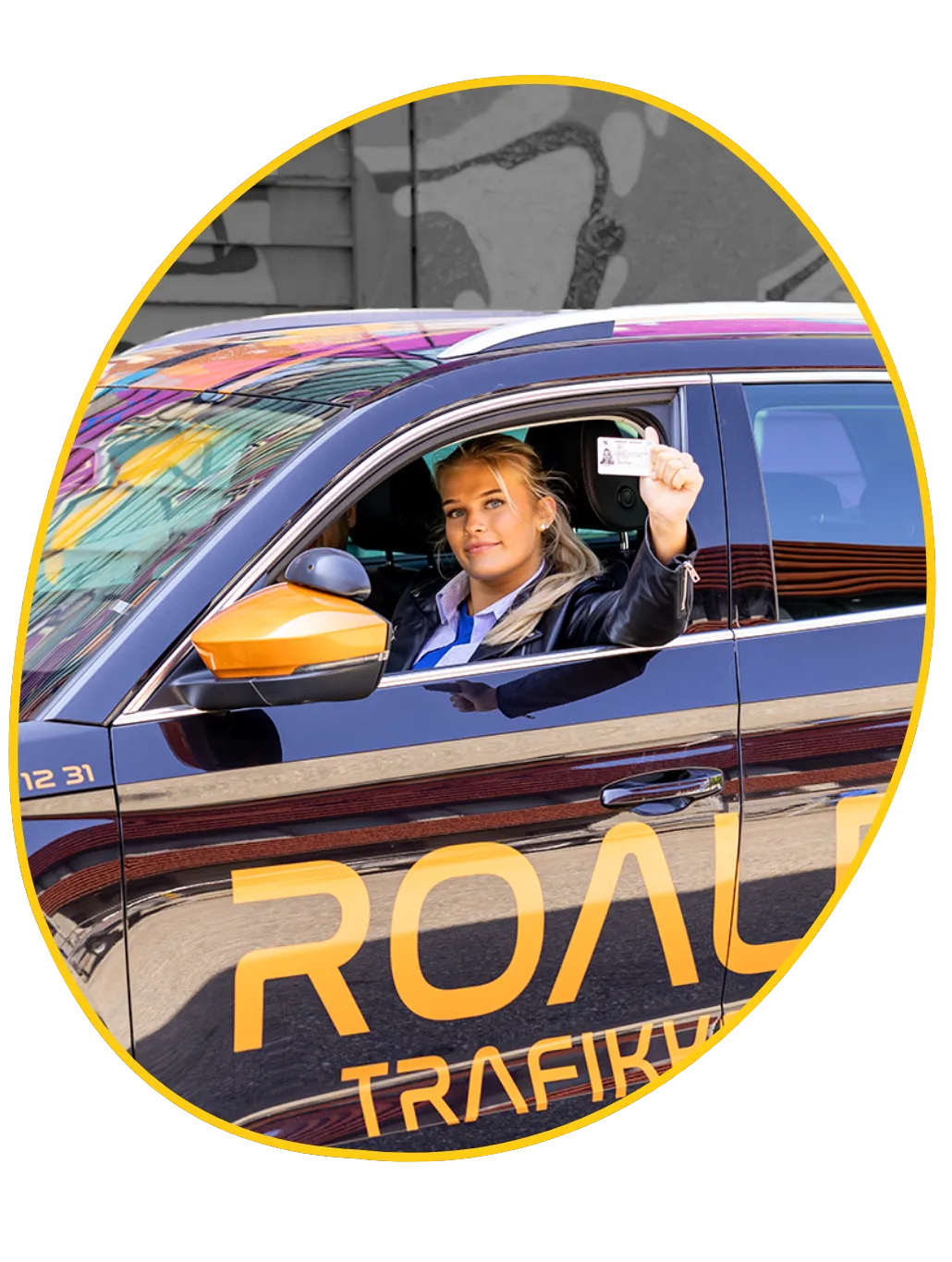 Elev som nettopp har bestått førerprøven i Bergen og viser førerkortet i bilen fra Roalds Trafikkskole.