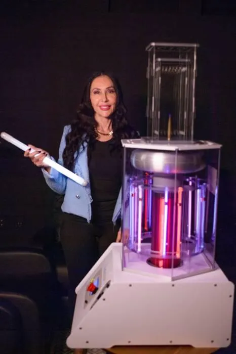 Woman demonstrating BioCharger electromagnetic wellness therapy for energy enhancement at OsteoStrong Upper West Side NYC