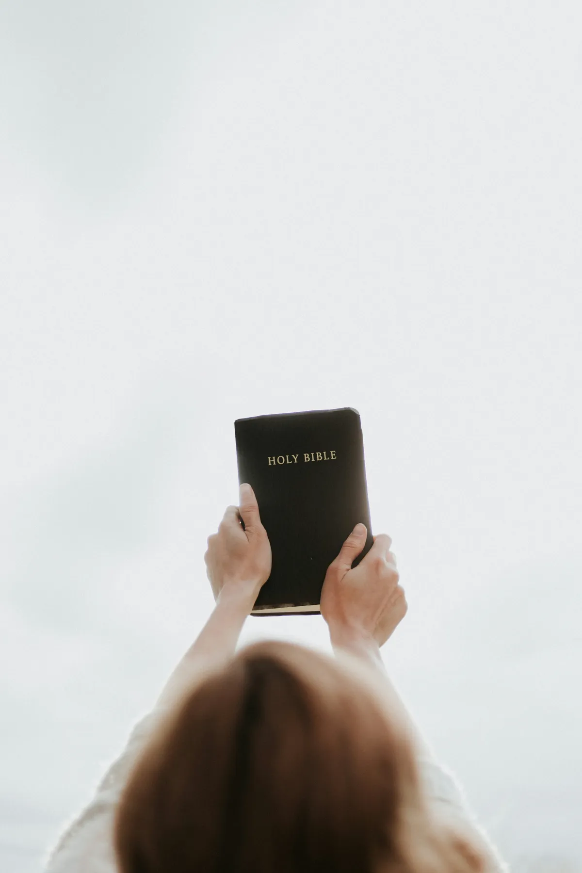 woman-looking-up-raising-bible-into-the-air