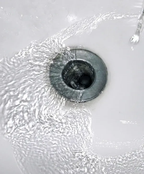 Clean water flowing smoothly into a sink drain after unclogging