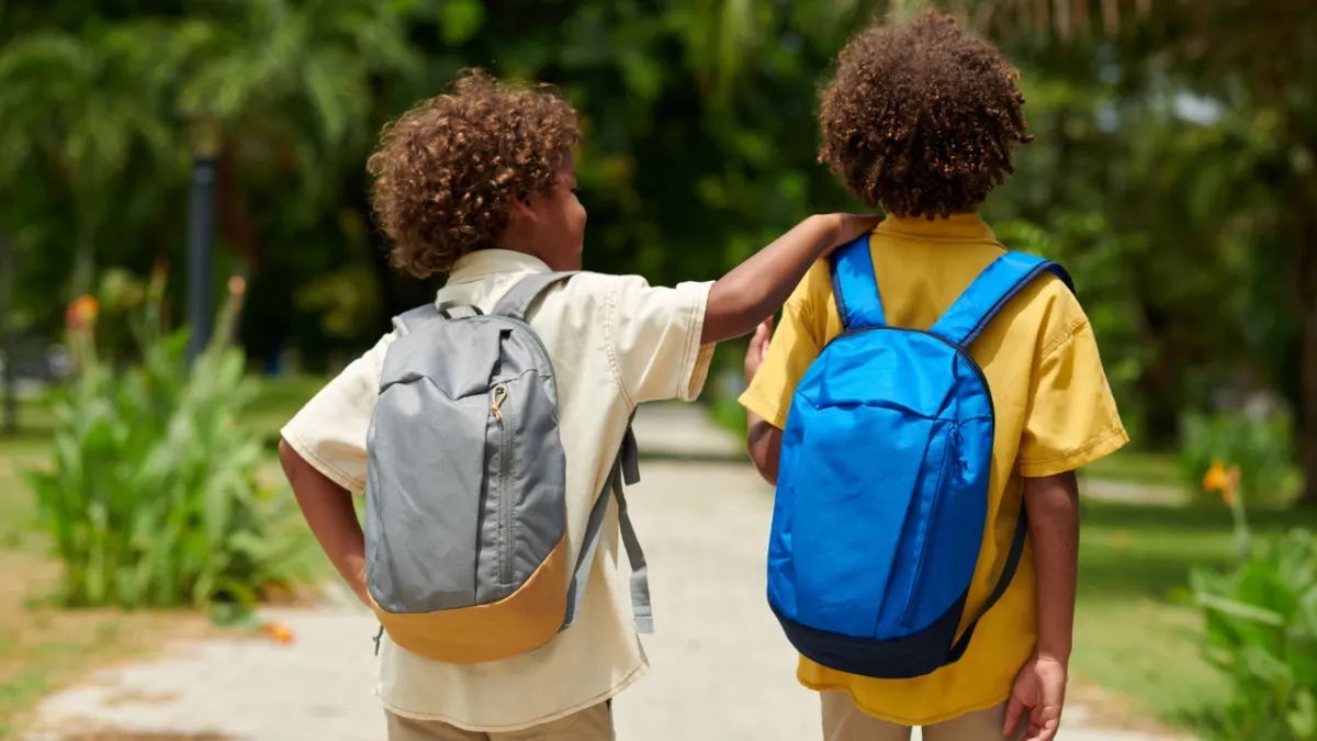 Two students wearing backpacks walking to school during back-to-school season for education tax planning tips.