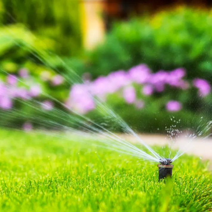 A landscaper adjusting sprinkler heads in an Austin garden to accommodate new plantings and optimize water usage.