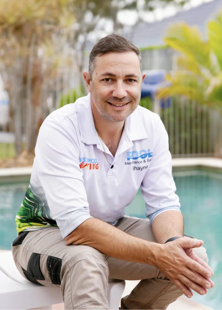 Founder Shayne Guy crouching by pool in branded white polo